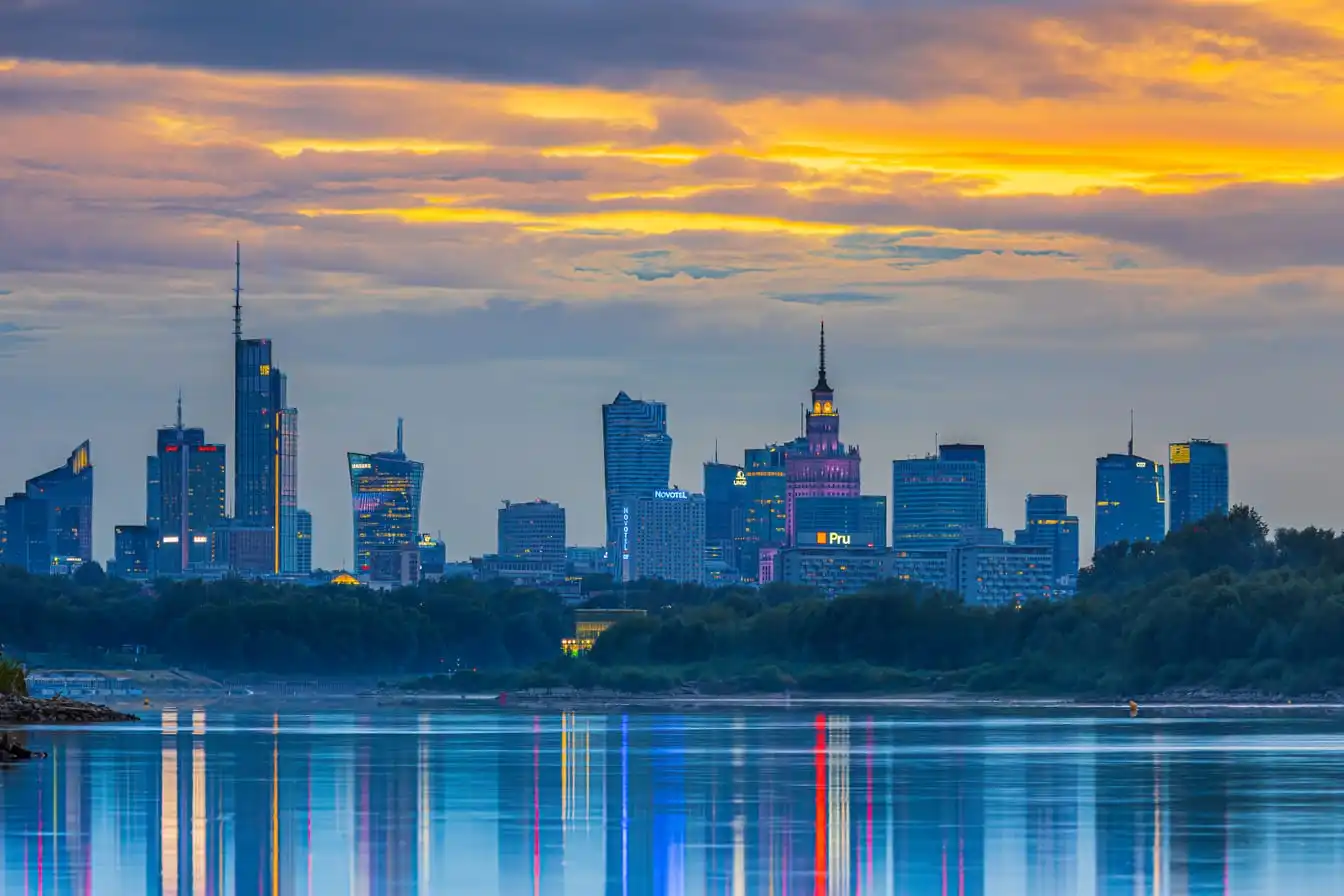Warsaw's skyline at sunset, reflected in the river.